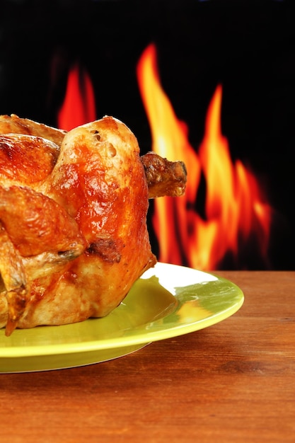 Foto pollo asado entero en un plato verde en un primer plano de fondo de madera