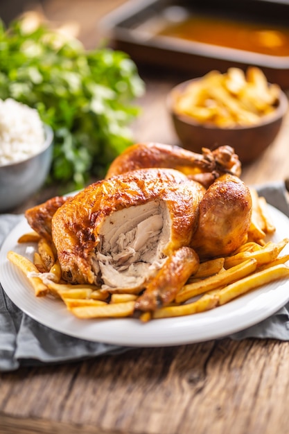 Pollo asado muy sabroso entero en un plato y mesa de madera.