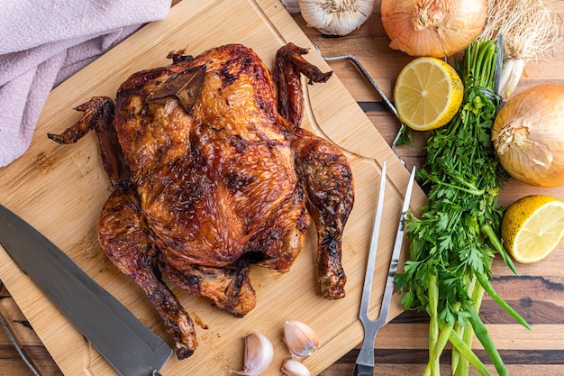 Pollo asado servido en la tabla de madera sobre la mesa.