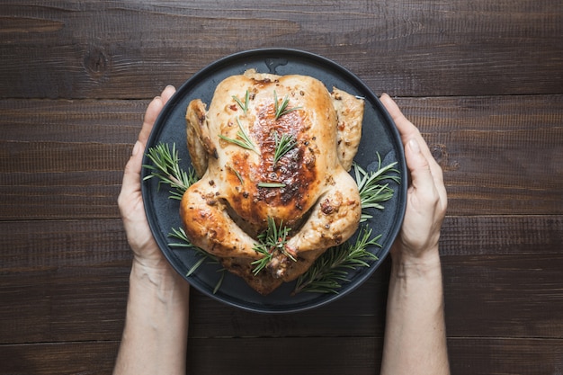 Foto el pollo asado tradicional adorna las verduras y el romero en la tabla de madera. vista superior.