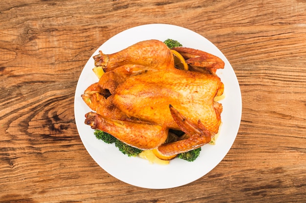 Foto pollo asado y verduras en la mesa de madera