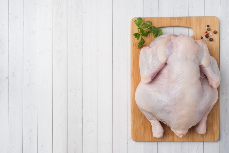 Pollo crudo fresco en tabla de cortar y especias para cocinar