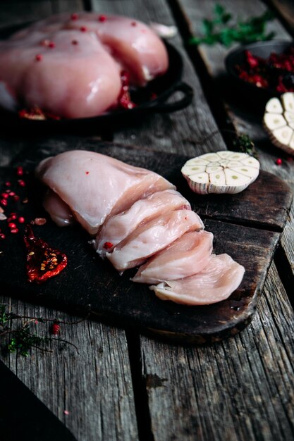 Pollo crudo sobre una mesa de madera con especias