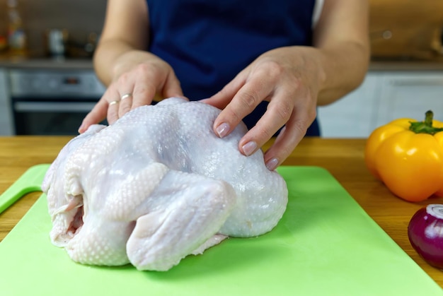 Pollo crudo en una tabla de cortar El cocinero comienza a preparar la cena en casa