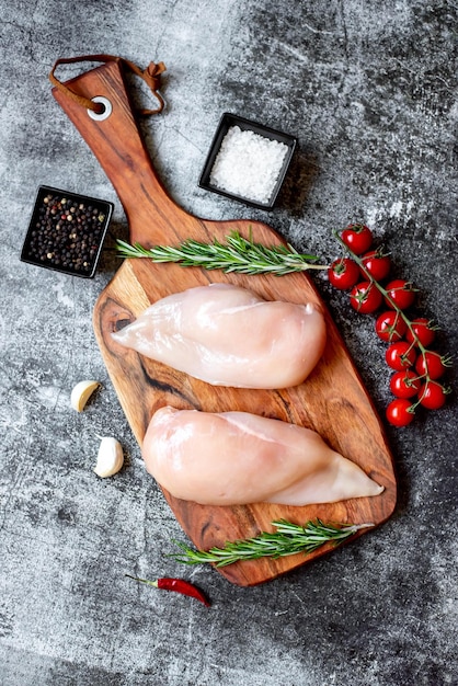 Pollo crudo en una tabla para cortar con especias y hierbas.