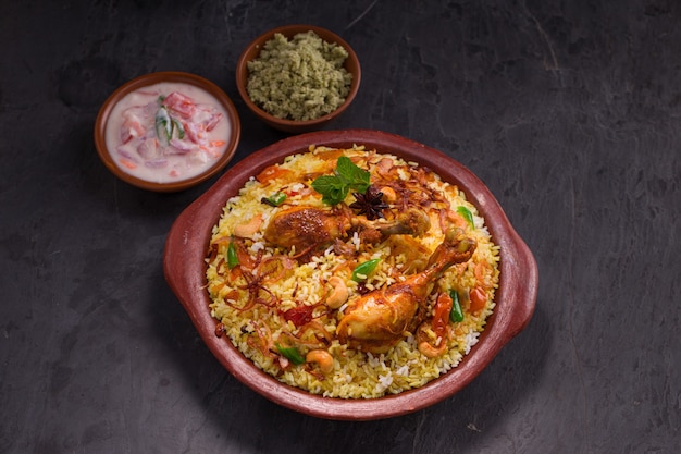 Pollo dhum biriyani con arroz jeera y especias dispuestas en loza de barro