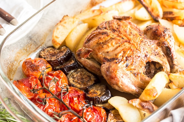 Foto pollo entero al horno con papas, berenjenas y tomates cherry. cena saludable