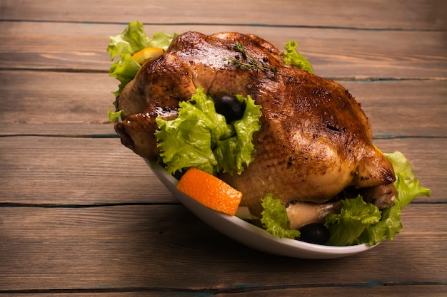 El pollo entero cocido con adorna sobre fondo de madera. Comida de vacaciones. Estilo rustico