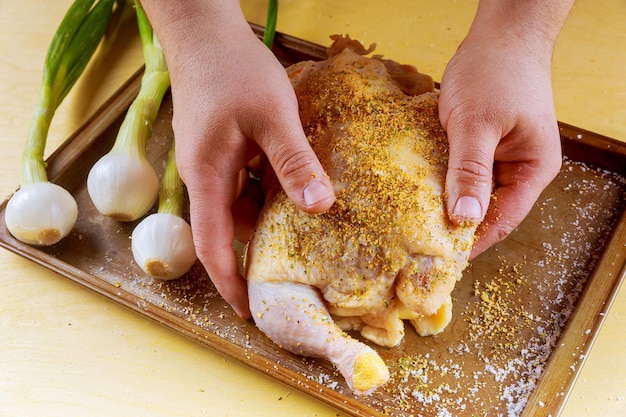 Pollo entero crudo con coloridos trozos de pimientos hojas de romero en la fuente para hornear preparándose para el asado