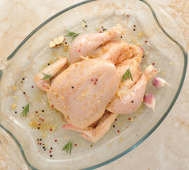 Pollo entero crudo en mesa de mármol