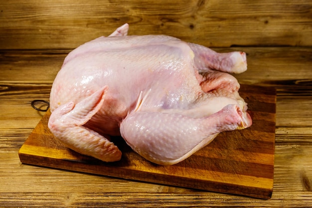 Pollo entero crudo sobre una mesa de madera