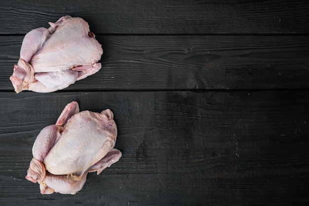 Pollo entero joven pequeño crudo, sobre fondo de madera negra