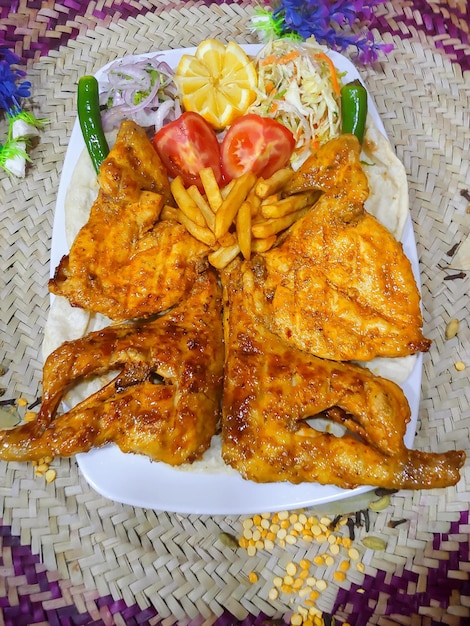 Pollo entero a la parrilla con papas fritas y limón servido en un plato aislado en la vista superior de la mesa de comida árabe