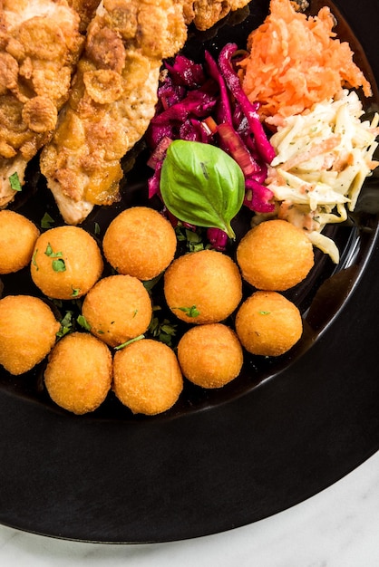 Pollo frito con bolas de patata y porción de restaurante de ensaladas