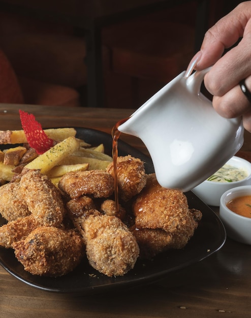 Pollo frito com papas fritas e cremes com um fundo de madeira.