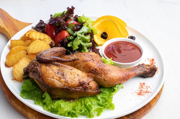 Pollo frito con papas y ensalada fresca en un plato blanco