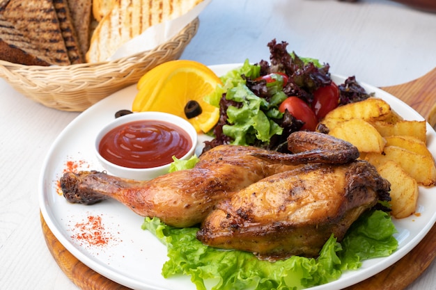 Pollo frito con papas y ensalada fresca en un plato blanco