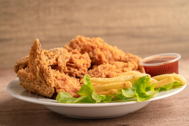 Pollo frito y papas fritas con hojas de romero, comida chatarra alta en calorías servida en un plato blanco