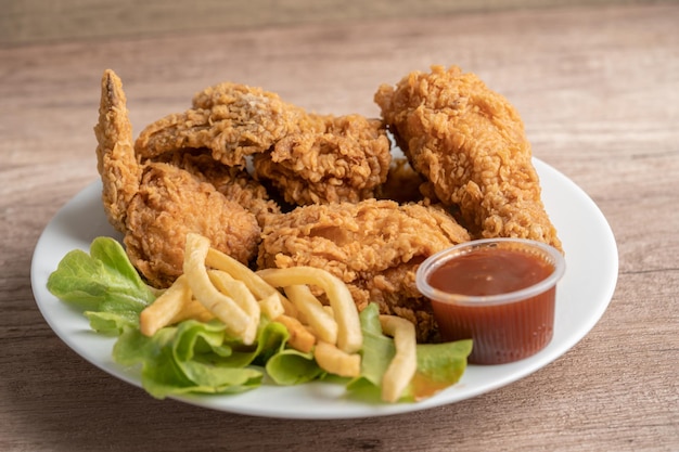 Pollo frito y papas fritas con hojas de romero, comida chatarra alta en calorías servida en plato blanco