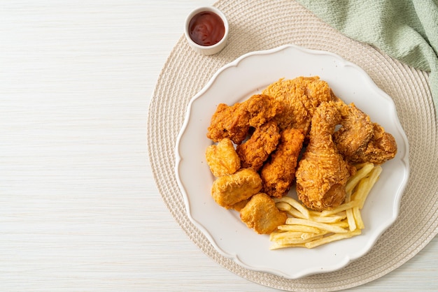 pollo frito con papas fritas y nuggets en el plato - comida poco saludable