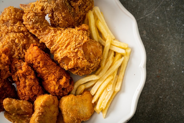 pollo frito con papas fritas y nuggets en el plato - comida poco saludable