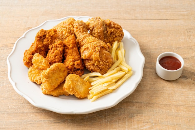 pollo frito con papas fritas y nuggets en el plato - comida poco saludable