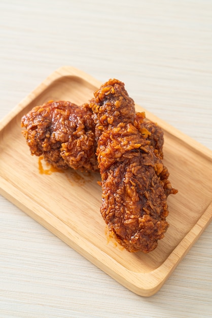 Pollo frito con salsa coreana picante en placa de madera