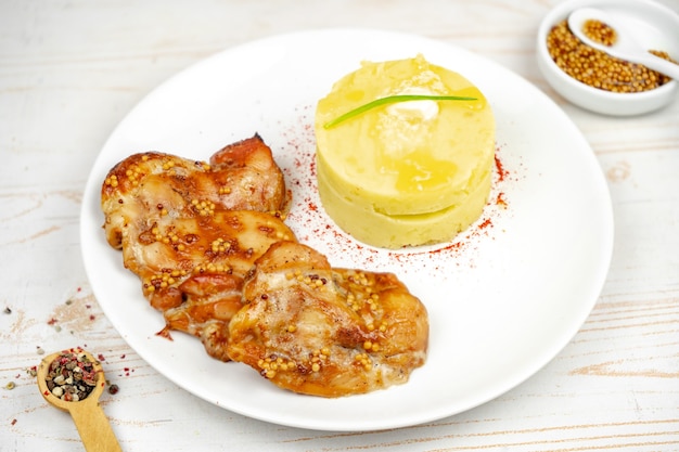 Pollo frito con salsa de mostaza y miel con puré de patatas en la placa blanca.