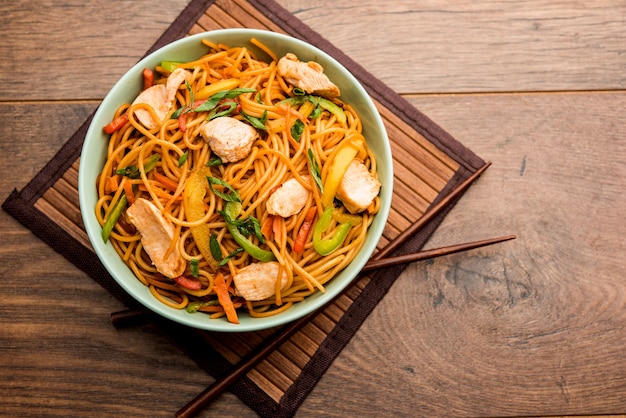 Pollo Hakka o fideos Schezwan servidos en un tazón con palillos