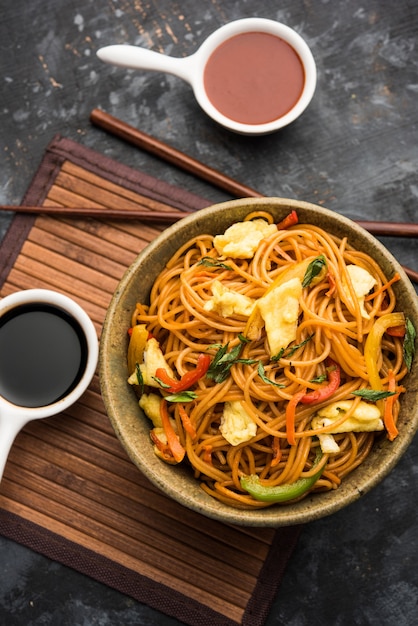 Pollo Hakka o fideos Schezwan servidos en un tazón con palillos