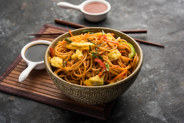 Pollo Hakka o fideos Schezwan servidos en un tazón con palillos