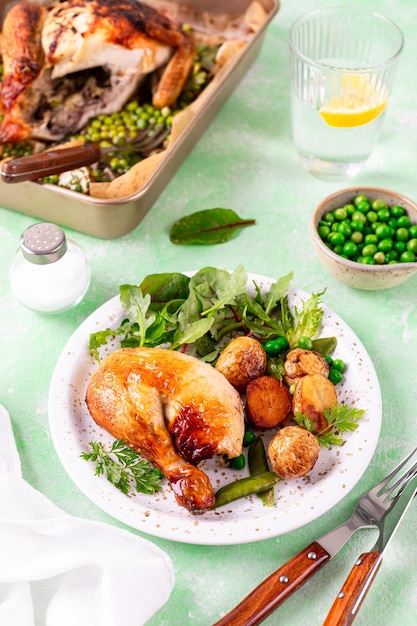 Foto pollo horneado con patatas y ensalada en un fondo verde