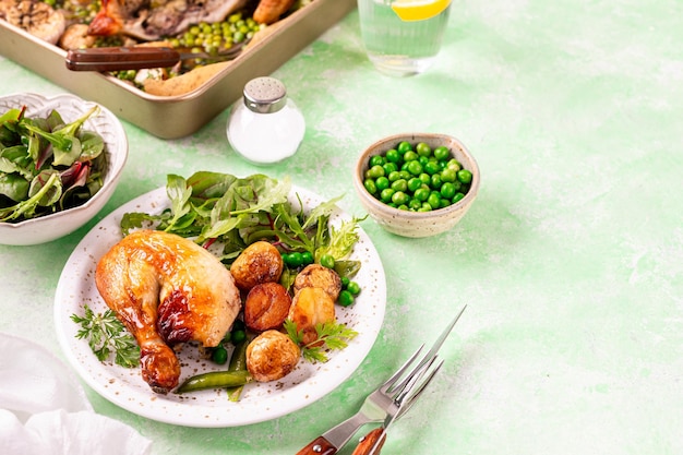 Pollo horneado con patatas y ensalada en un fondo verde