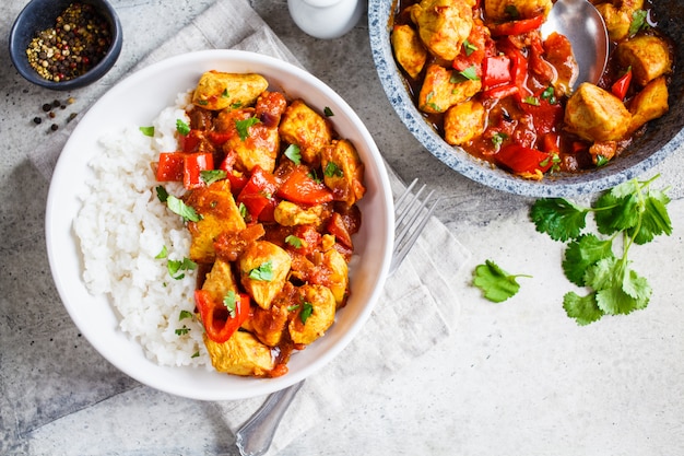 Pollo Jalfrezi con arroz en un tazón blanco, vista superior, espacio de copia. Concepto de cocina tradicional india.