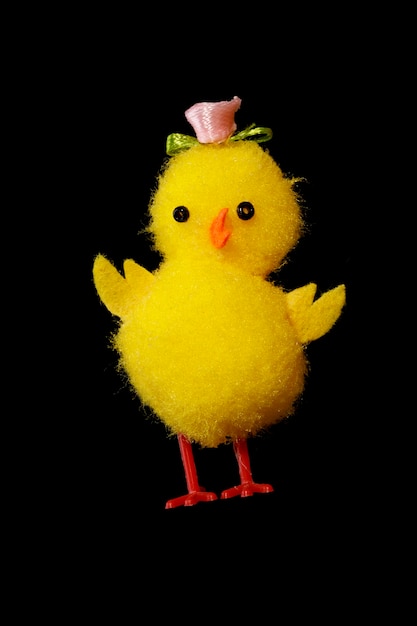 Pollo de juguete aislado sobre fondo negro. pollito amarillo gracioso. Foto de alta calidad