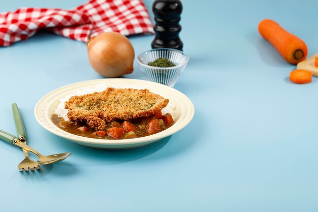 Pollo Katsu con Curry Japonés, Servir con Arroz Blanco en un Plato de Cerámica Crema, Fondo Azul. Copiar espacio para texto