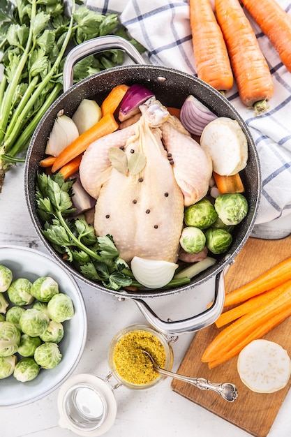 Pollo listo para cocinar caldo con tubérculos frescos y especias - vista superior.