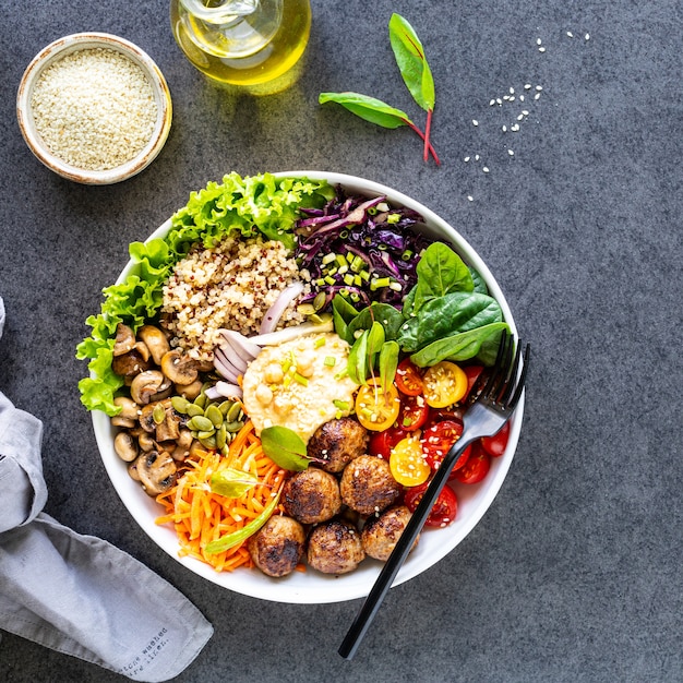 Pollo a la parrilla, arroz, garbanzos picantes, aguacate, repollo, tazón de Buda de pimienta sobre una superficie oscura, vista superior. Concepto de deliciosa comida equilibrada