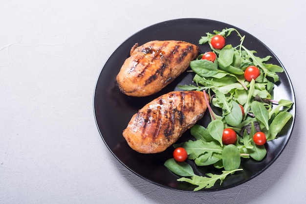 Pollo a la parrilla con ensalada de espinacas y tomates Fondo de comida BBQ