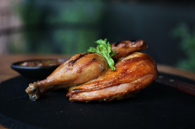 Pollo a la parrilla sobre fondo de madera de plato negro