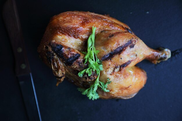 Pollo a la parrilla sobre fondo de madera de plato negro