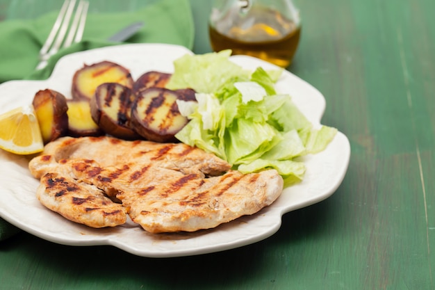 Pollo a la parrilla con verduras en plato blanco