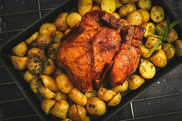 Pollo con patatas en una fuente para horno sobre una rejilla de alambre de hierro