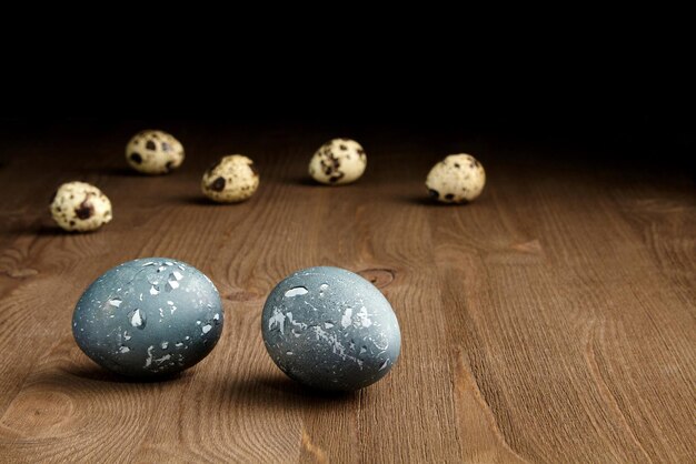 Pollo pintado y huevos de codorniz sobre una mesa de madera marrón sobre un fondo oscuro