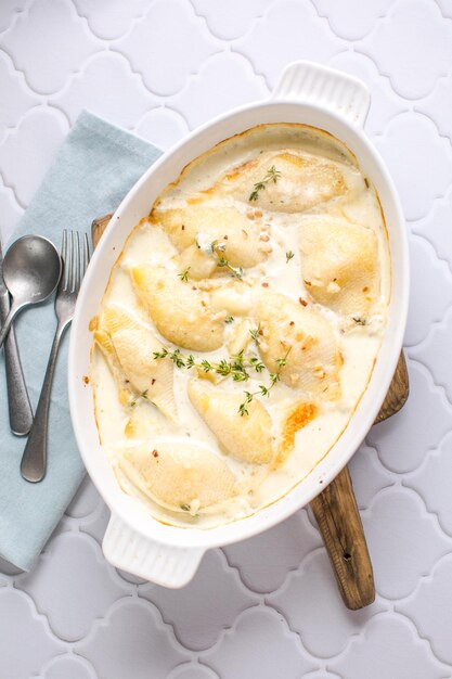 Pollo con queso y cremoso y pasta de conchas horneada en un plato para hornear sobre una mesa de hormigón gris oscuro vista horizontal desde arriba del primer plano