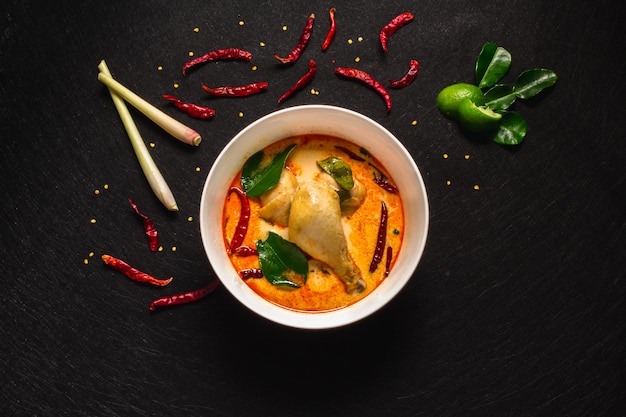 Pollo a la sopa de coco picante, al curry tailandés de coco. Fondo oscuro y vista superior.