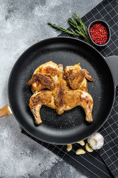 Pollo tabaka crudo en sartén