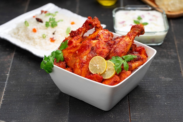 Pollo Tandoori picante adornado con hojas de cilantro en un tazón blanco de forma cuadrada