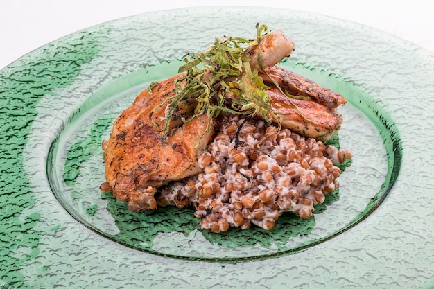 Foto pollo tapaka tabaka tabaco con risotto de trigo sobre fondo blanco.