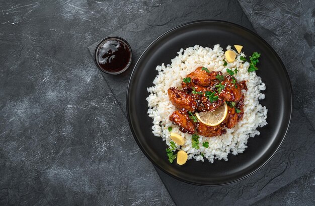 Pollo teriyaki japonés con arroz sobre un fondo oscuro